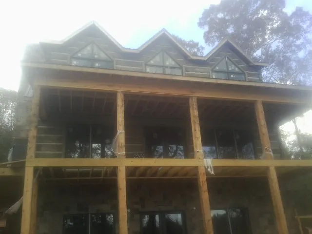 Dormers and porch framing on a large log home under construction — Roof Coating work by our crew in Seaside Park