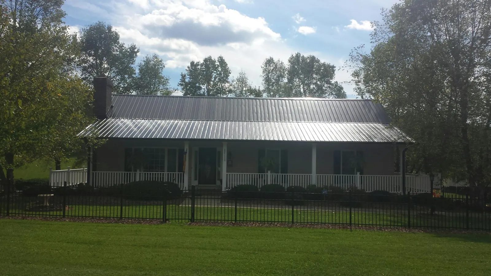 Gray metal roof on a brick ranch with a full width front porch — Gutter Guard Installation work by our crew in Seaside Park