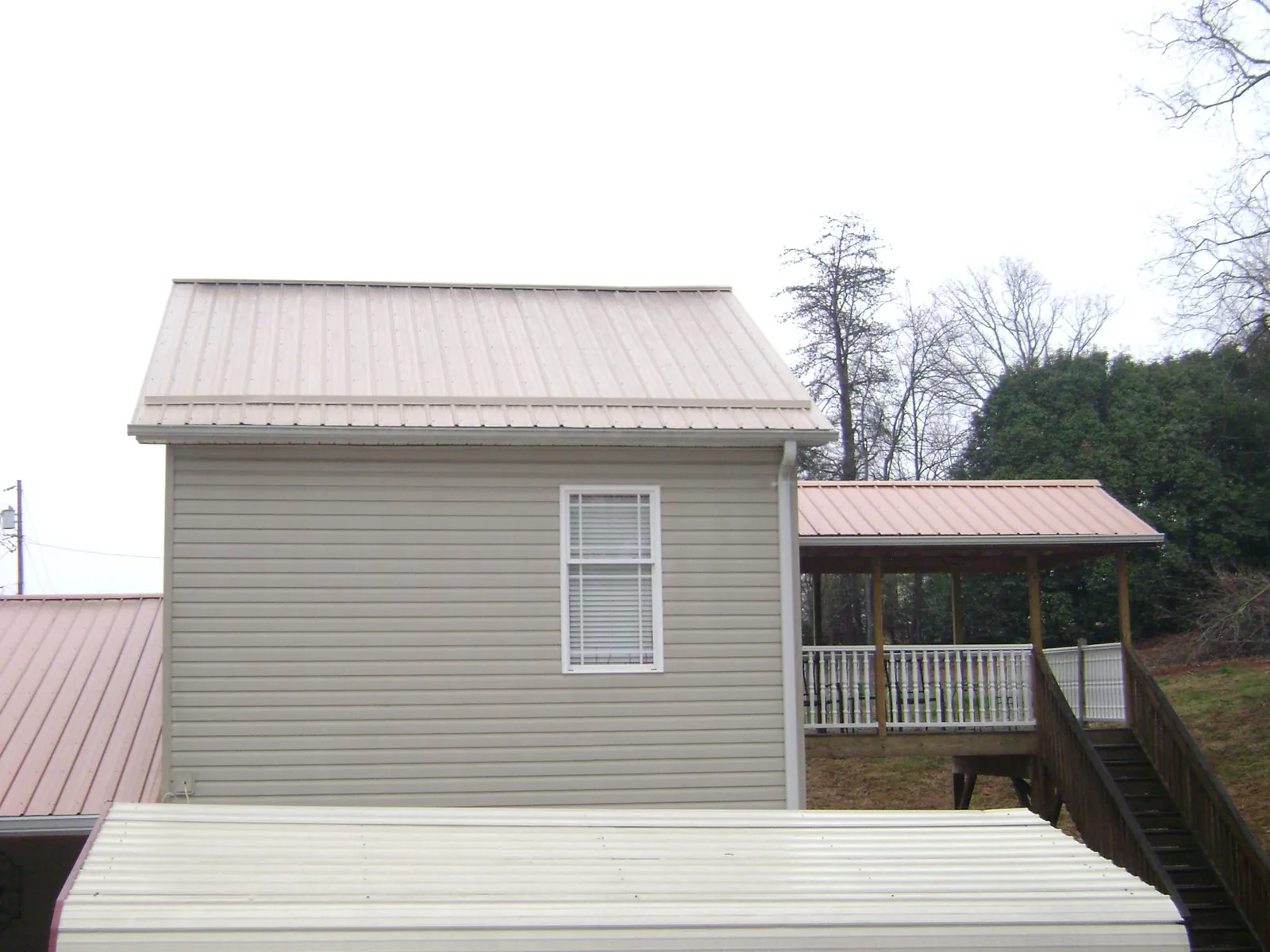 Tan metal roofs on a two story addition and attached porch, from a Roof Replacement job in Seaside Park