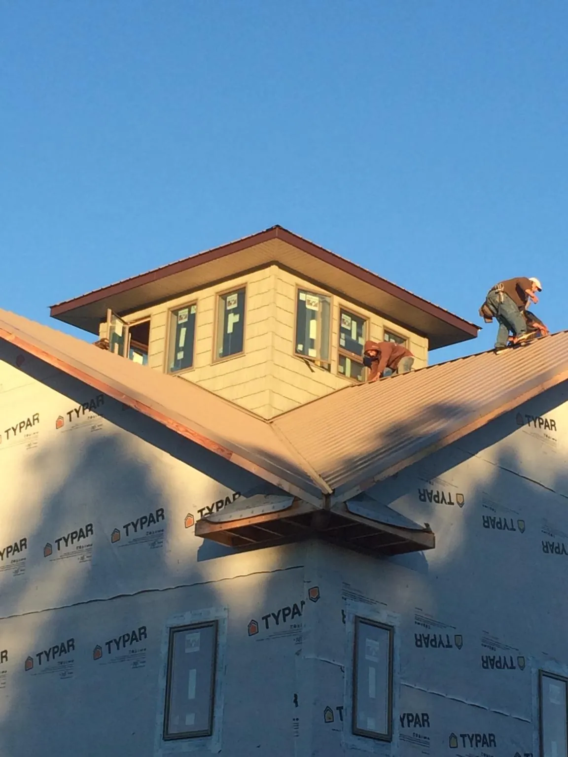 Roofers working around a rooftop cupola on a new metal roof at sunset — Roof Waterproofing in Seaside Park by Roofing Brothers
